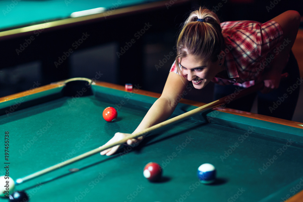 Fototapeta premium Young attractive woman playing pool in bar