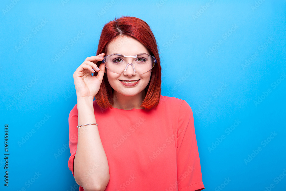 Nerd redhead woman wearing science glasses on blue background Nerd redhead woman wearing science glasses on blue background