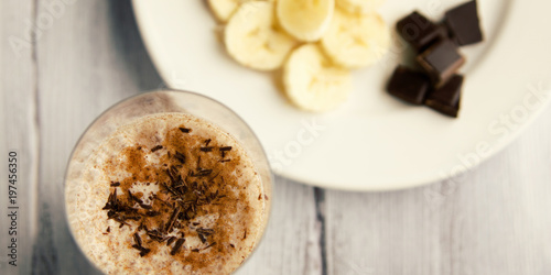 Banana chocolate smoothie with a dash of cinnamon. A glass of milk smoothie sprinkled with chocolate. Healthy breakfast. Lacto vegetarian dish. Top view. photo