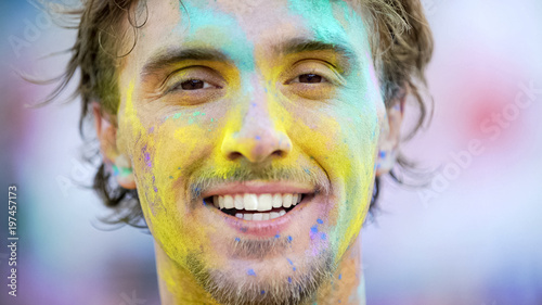Fototapeta Naklejka Na Ścianę i Meble -  Close up of handsome male face covered in colors, happy man smiling to camera