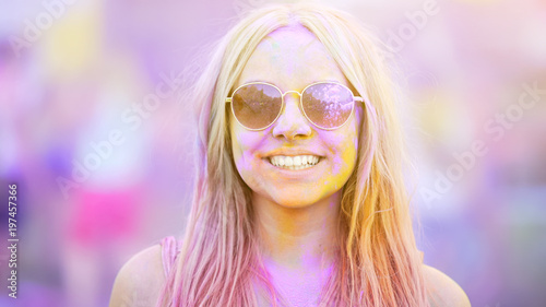Smiling girl in sunglasses covered in colorful dyes, summer vacation, youth © motortion