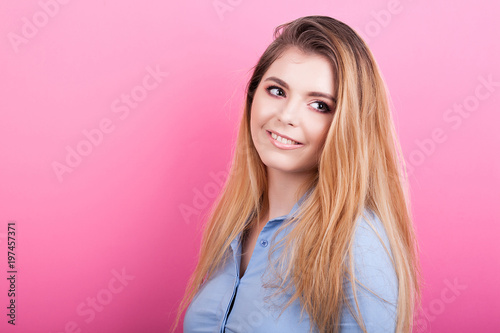 Smiling blonde woman on pink background in studio photo