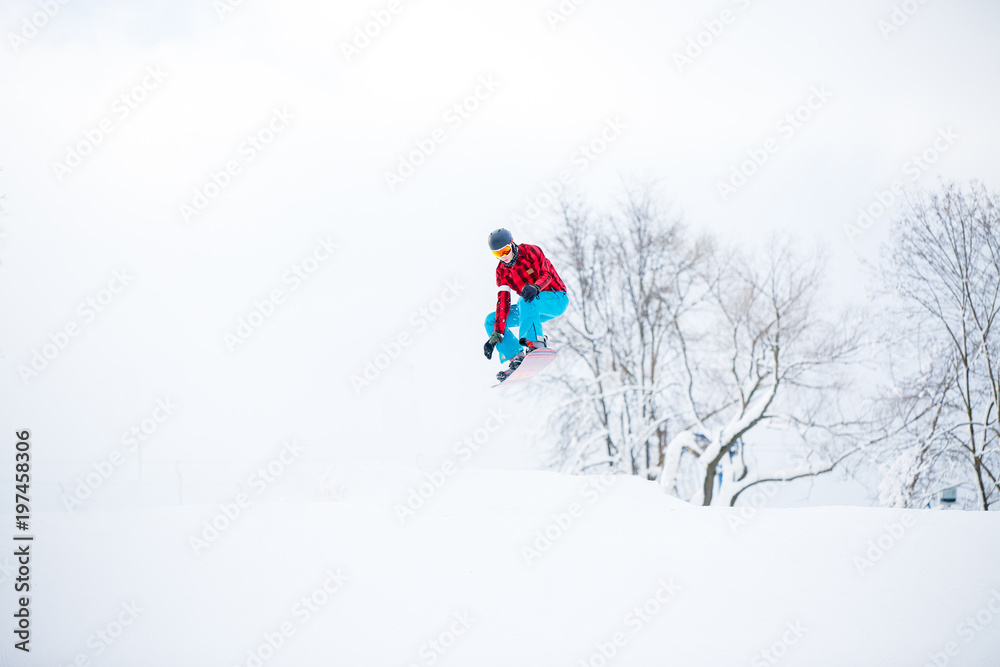 Photo of snowboarder man jumping on snowy hill