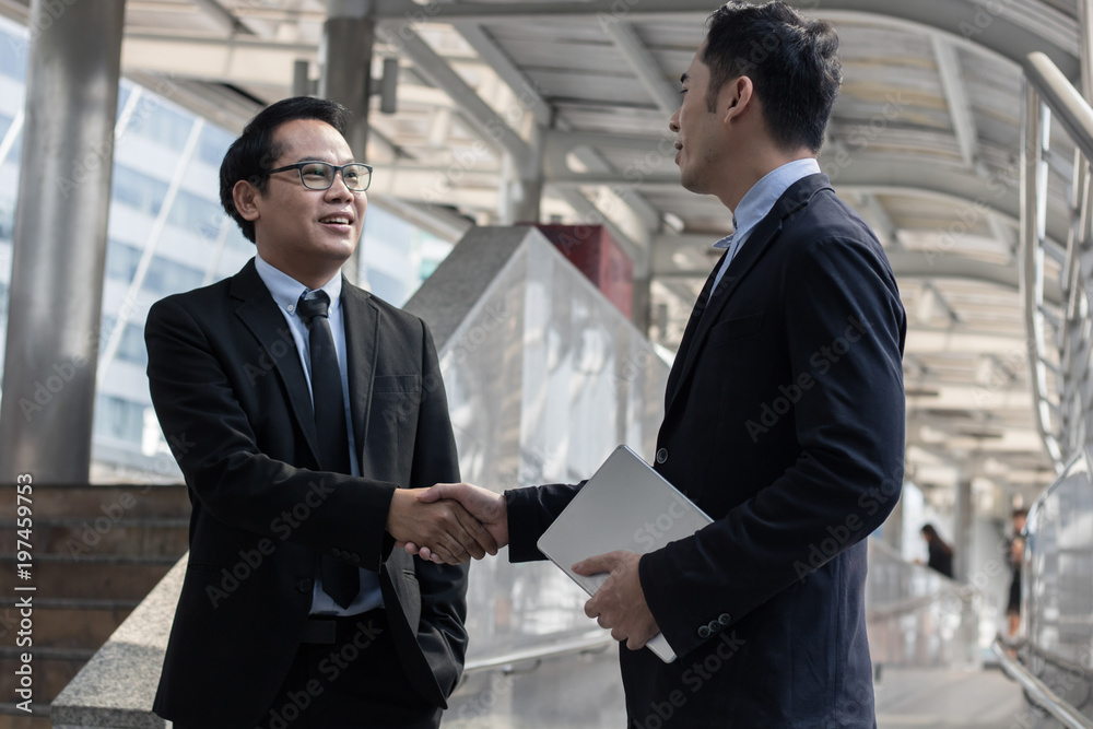 Successful negotiating business concept, Businessmen shaking hands after finishing meeting or setting  goals and planning way to success in front of building .