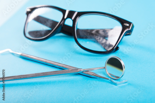 Dentistry set of tools and glasses on blue background.
