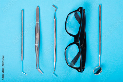 Dentistry set of tools and glasses on blue background.