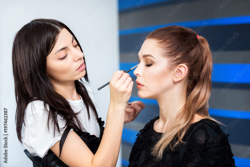 Professional artist is making beauty makeup to a young woman using a brush. Professional artist is making beauty makeup to a young woman using a brush.