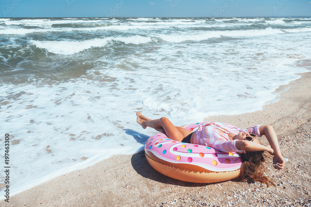 Girl relaxing on donut lilo on the beach Girl relaxing on donut lilo on the beach