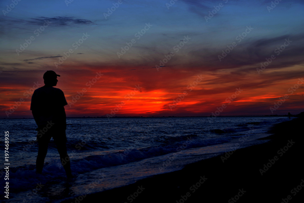 Sunset over lake or sea and the silhouette of man