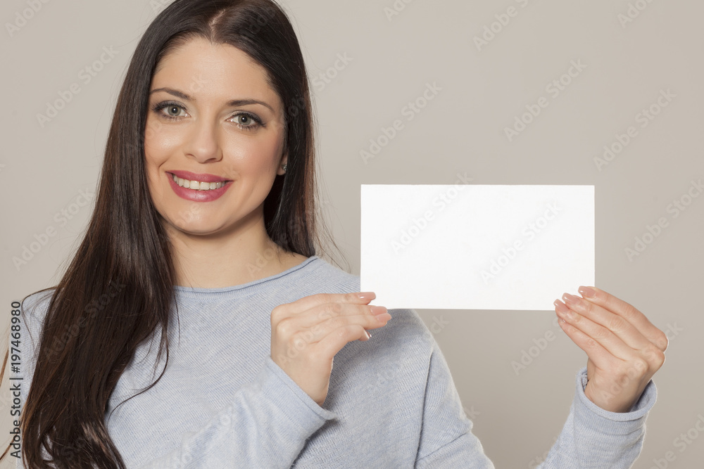 Smiling woman showing empty blank paper card sign with copy space for text Smiling woman showing empty blank paper card sign with copy space for text