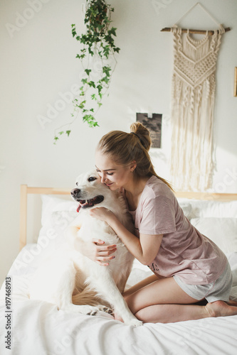 светловолосая девушка в пижаме обнимает свою собаку blonde girl in pajamas hugging her dog Labrador