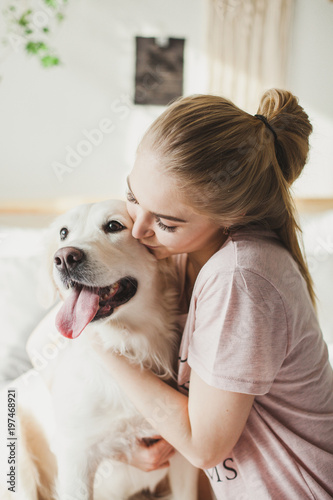 светловолосая девушка в пижаме обнимает свою собаку blonde girl in pajamas hugging her dog Labrador
