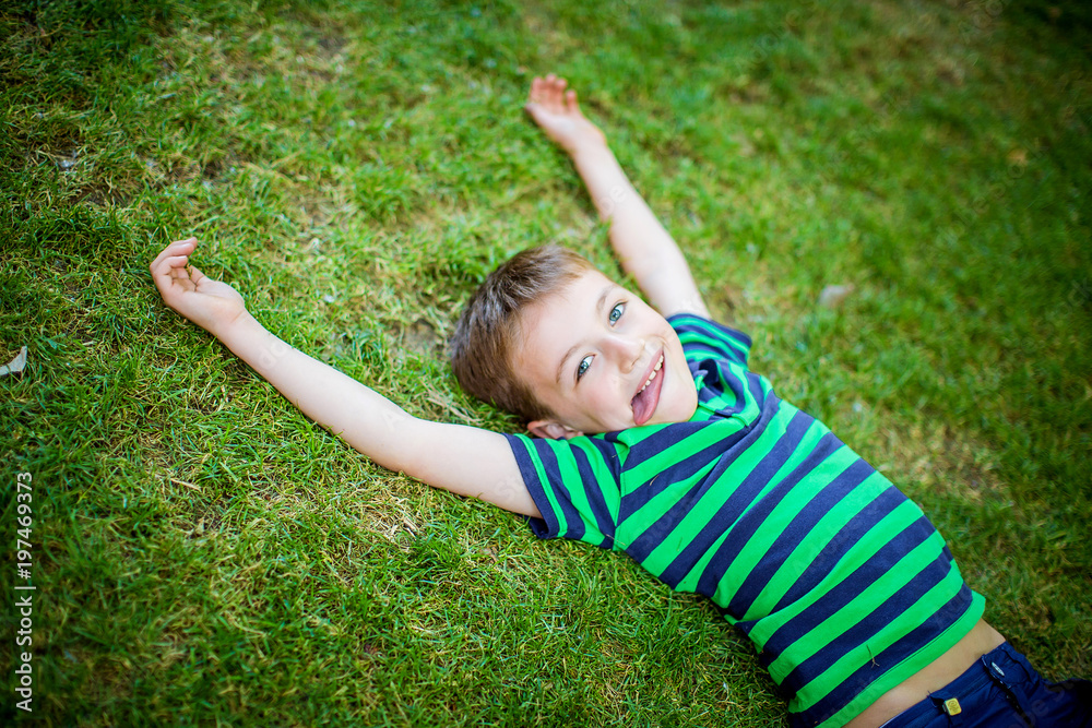 Little happy boy lies on the green grass Little happy boy lies on the green grass