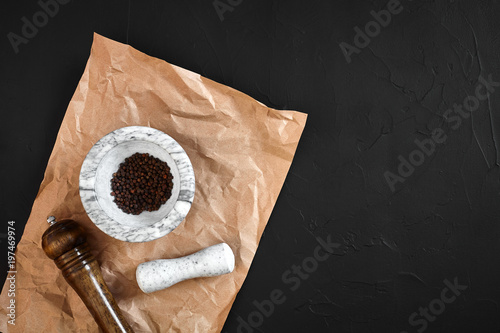 White mortar and pestle with dried peppers in flat lay on black background photo