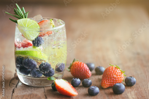 Infused water made from blueberry strawberry and lemon in sparkling mineral water look so freshness and healthy. Mixed fruit mojito on wood table with copy space. Summer refreshing drink concept.