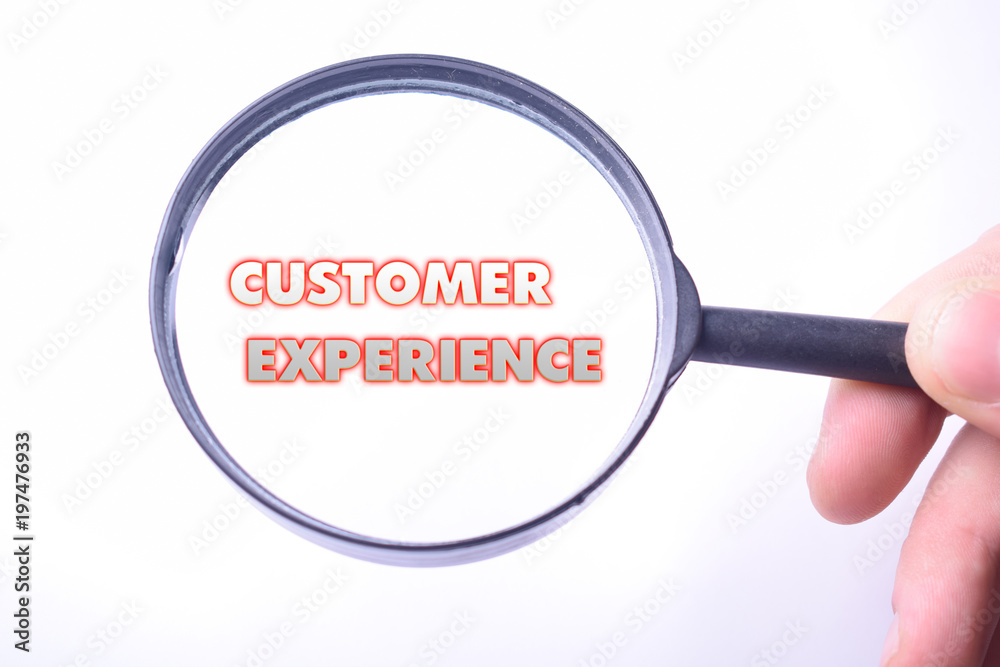 Businessman looking at a magnifying glass word:CUSTOMER EXPERIENCE Businessman looking at a magnifying glass word:CUSTOMER EXPERIENCE