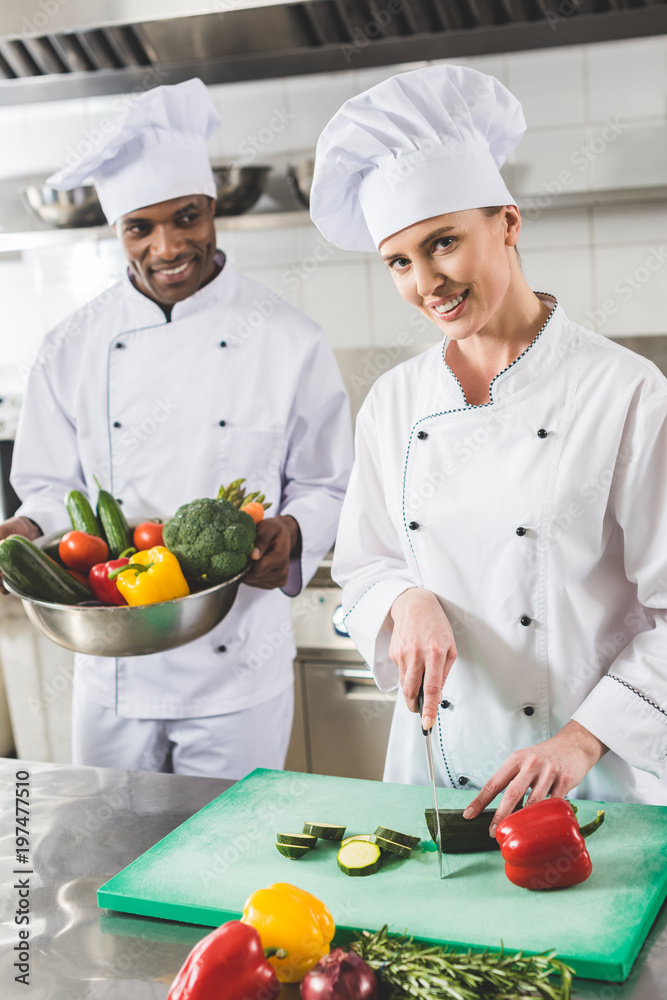 smiling multicultural chefs cooking at restaurant kitchen smiling multicultural chefs cooking at restaurant kitchen