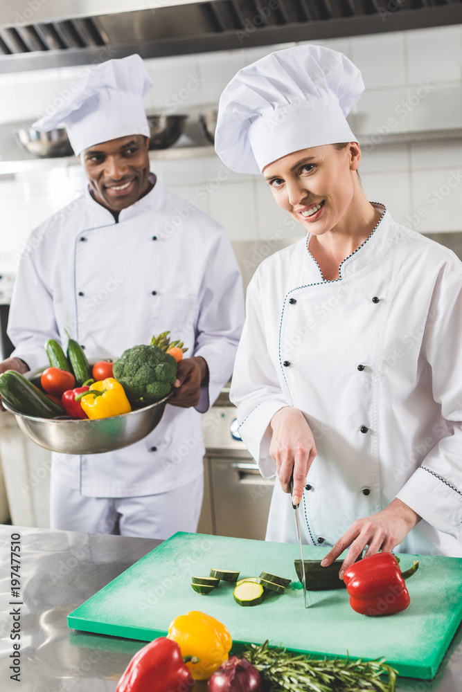 smiling multicultural chefs cooking at restaurant kitchen