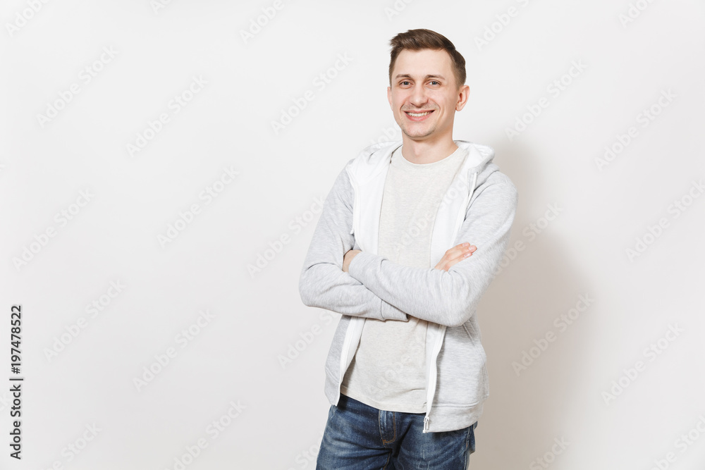 Young handsome smiling man student in t-shirt and light sweatshirt crossed his arms over chest, rejoices isolated on white background. Concept of emotions, good mood. Copy space for advertisement. Young handsome smiling man student in t-shirt and light sweatshirt crossed his arms over chest, rejoices isolated on white background. Concept of emotions, good mood. Copy space for advertisement.