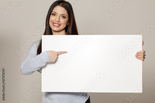 Happy woman showing empty blank paper card sign with copy space for text