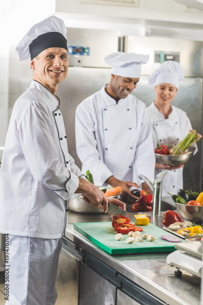 multicultural chefs cutting and washing vegetables at restaurant kitchen