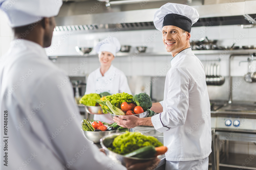 multicultural chefs holding bowls with vegetables at restaurant kitchen multicultural chefs holding bowls with vegetables at restaurant kitchen