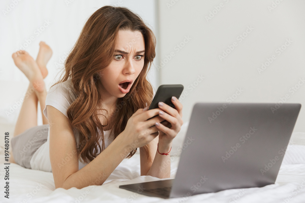 Portrait of a surprised young woman holding mobile phone Portrait of a surprised young woman holding mobile phone