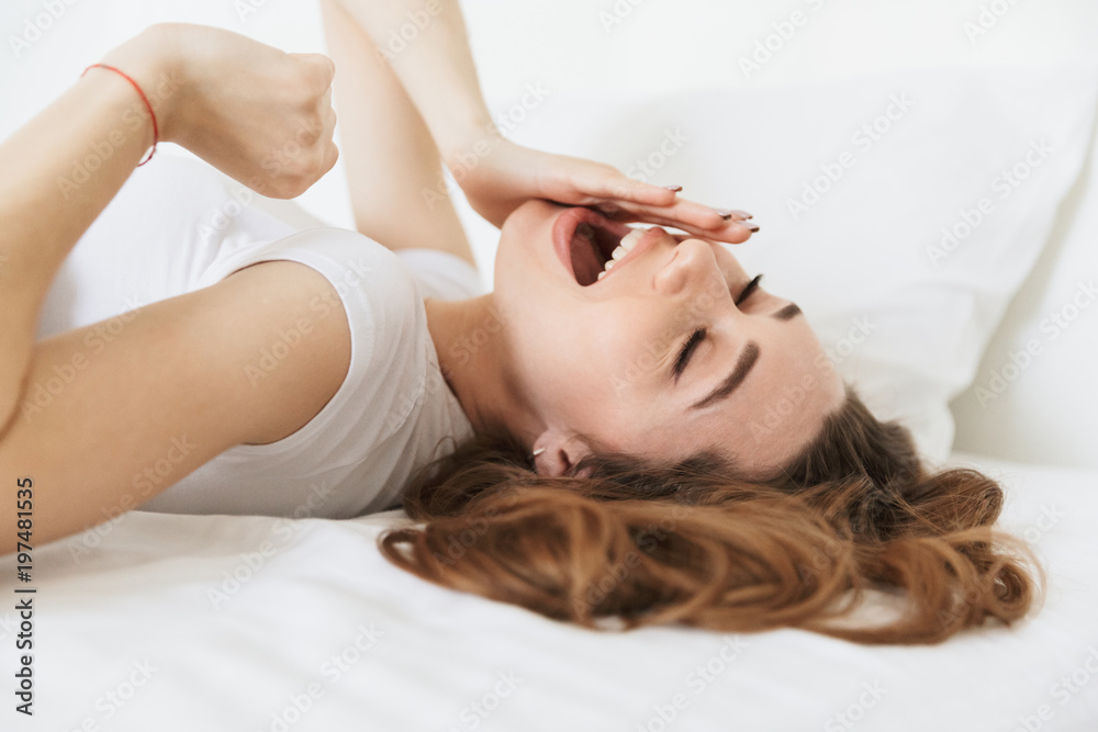 Portrait of a sleepy young woman laying in bed Portrait of a sleepy young woman laying in bed