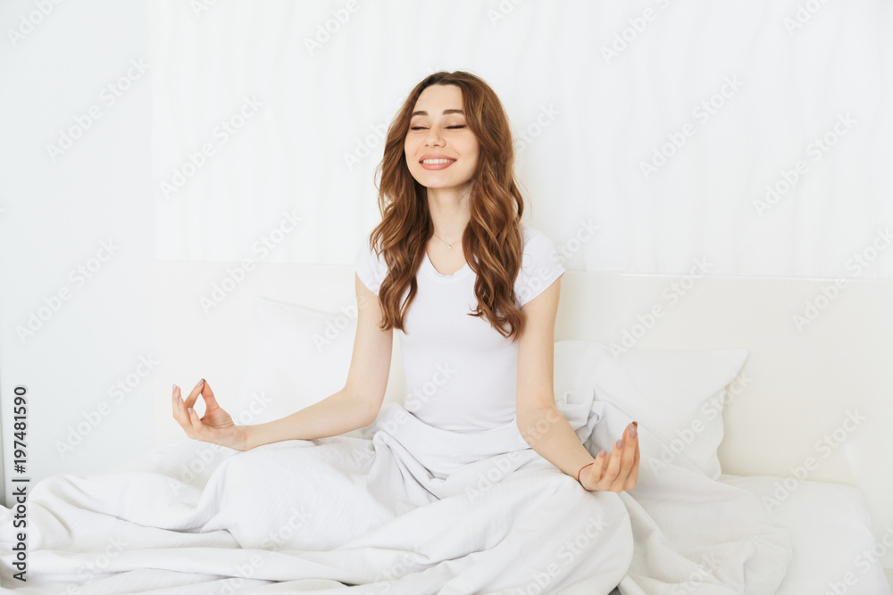 Portrait of a happy young woman meditating on bed Portrait of a happy young woman meditating on bed
