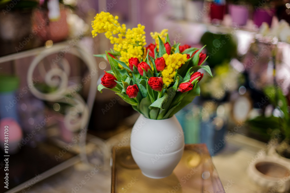 Beautiful red tulips and yellow mimosa in a blue vase