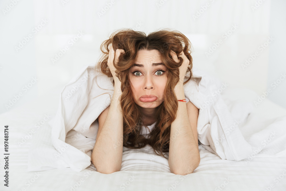 Portrait of an upset young woman lying in bed u Portrait of an upset young woman lying in bed u