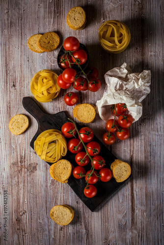 Fototapeta Naklejka Na Ścianę i Meble -  Top view on small cherry tomatoes on several twigs with tagliatelle