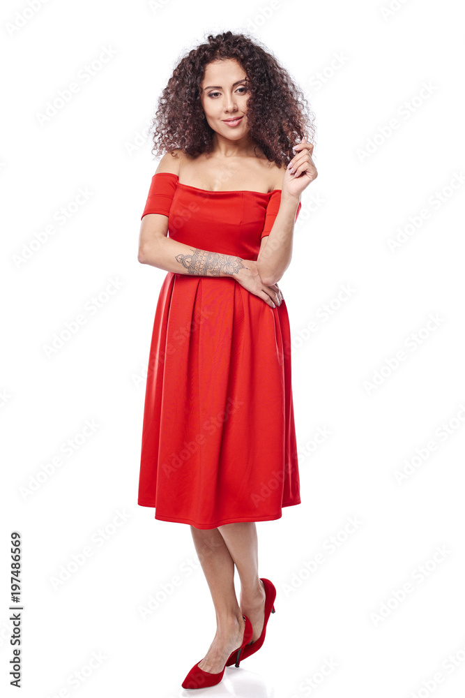 Beautiful curly female in red dress and red high heels shoes in full length touching her hair in thoughts Beautiful curly female in red dress and red high heels shoes in full length touching her hair in thoughts