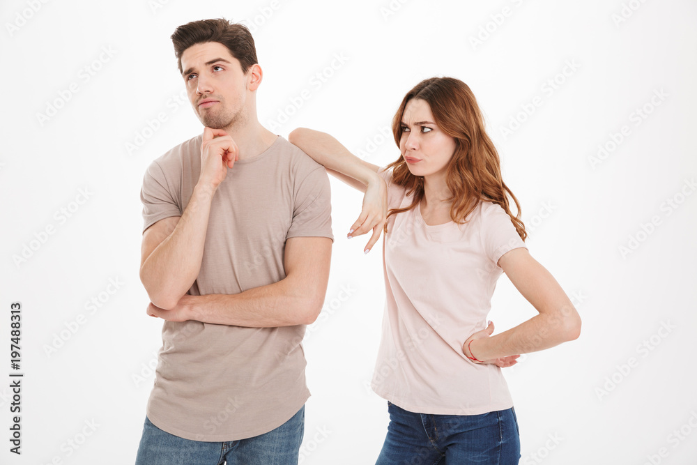 Photo of adult guy and girl wearing beige t-shirts acting like arguing couple and not speaking to each other in quarrel, over white background