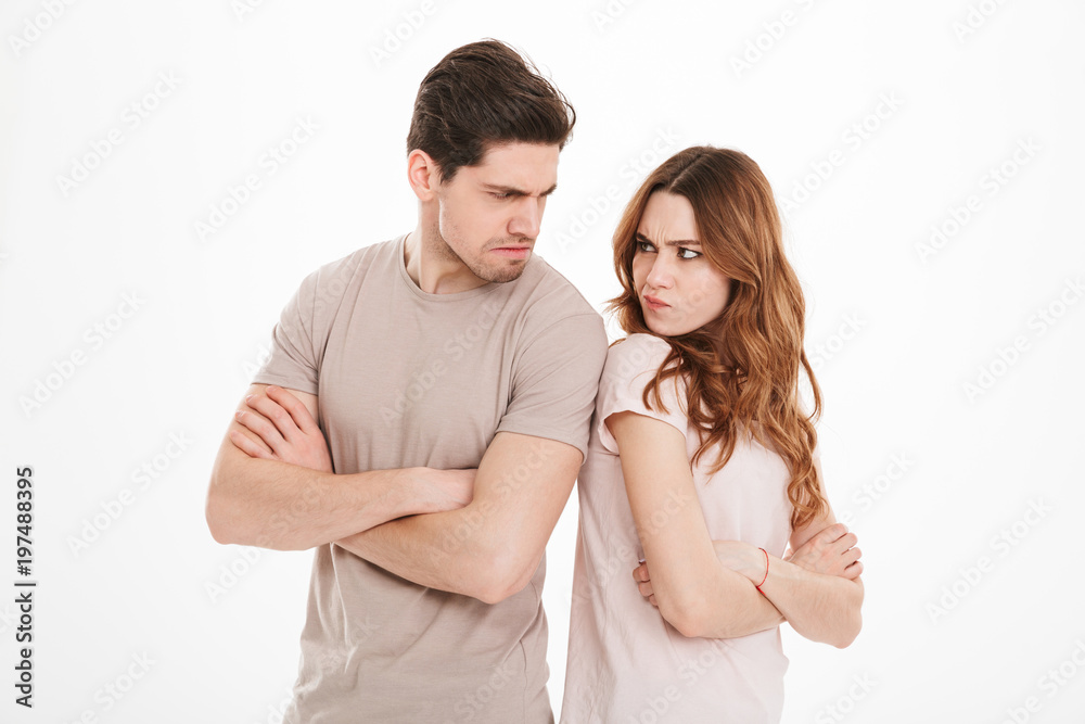 Photo of adult guy and girl wearing beige t-shirts acting like arguing couple and not speaking to each other standing back to back with crossed arms, over white background Photo of adult guy and girl wearing beige t-shirts acting like arguing couple and not speaking to each other standing back to back with crossed arms, over white background