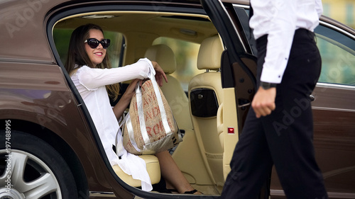 Luxury taxi service, chauffeur opening car door for female passenger, travel photo