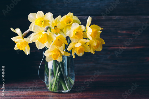 Fototapeta Naklejka Na Ścianę i Meble -  flowers daffodil in a glass vase on a wooden background
