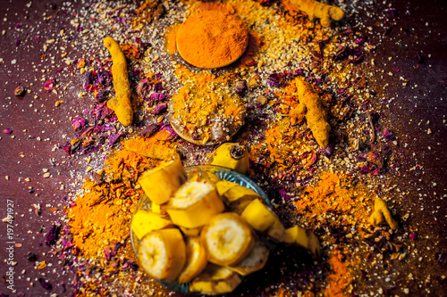 Fototapeta Naklejka Na Ścianę i Meble -  Close up of FACE PACK OF BANANA with all its other ingredients i.e. Turmeric powder, rose petals, and raw turmeric on a wooden surface for good and brighter skin.