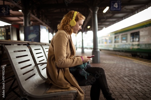 Beautiful young woman listing music while using her mobile phone