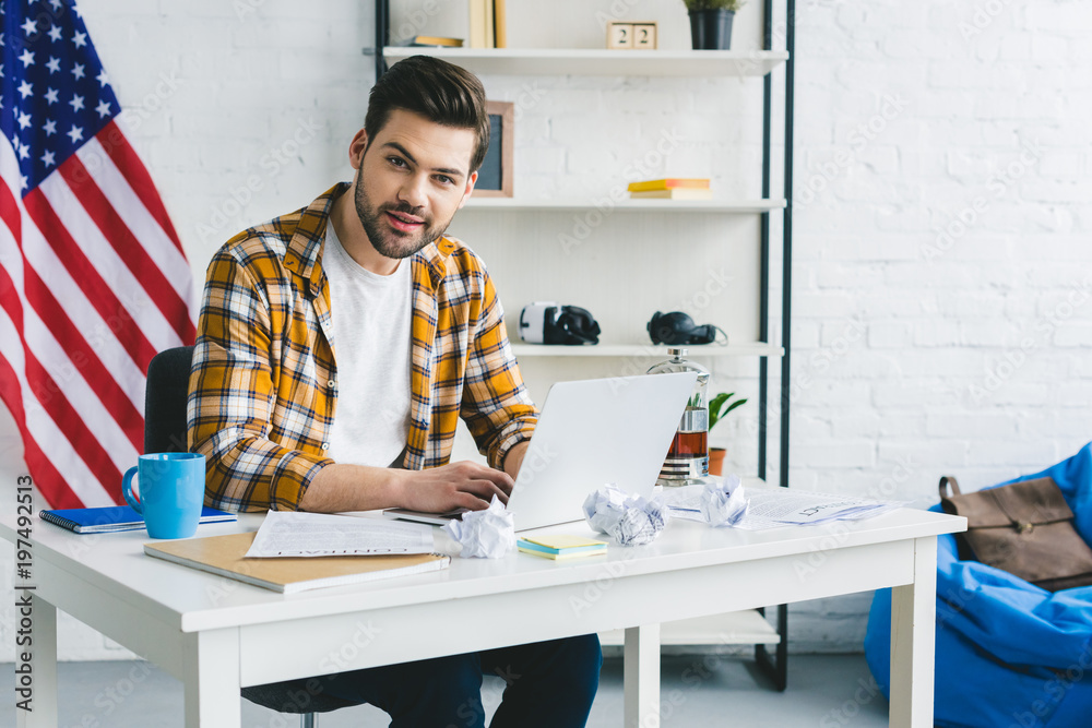 Man working by table with laptop in light office Man working by table with laptop in light office