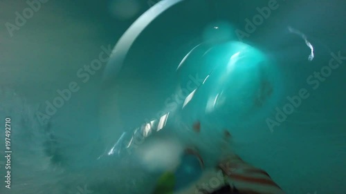 First-person view. Young man is having fun sliding down the water slide at the aquapark