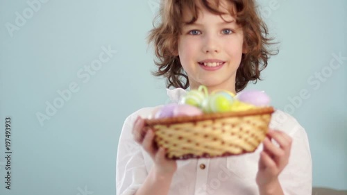 Portrait of a cheerful curly red-haired boy with an Easter basket in hands on a blue background photo