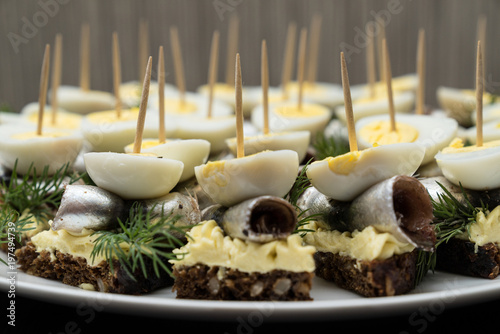 Mini sandwich with salt sprat and sliced boiled quail egg on the slice of bread. Canned fish is Estonian national food.   Concept of food and organic farm products.