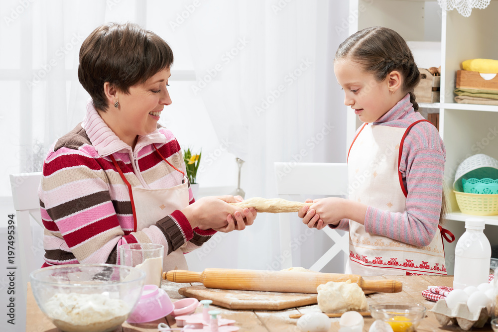 Mother and daughter cooking at home, making the dough for buns Mother and daughter cooking at home, making the dough for buns