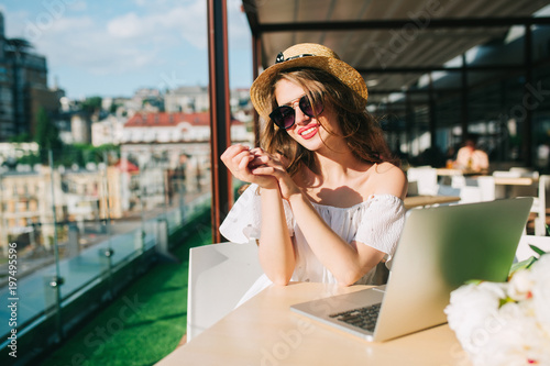 фотографія Pretty  girl with long hair in sunglasses sits at  table on the terrace in cafe