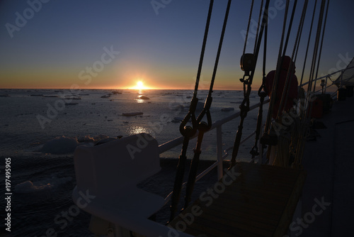 sunrise at the arctic sea with a sail boat in front