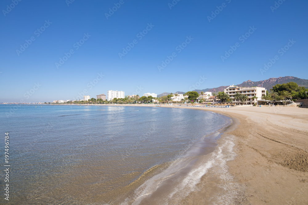 sandy and lonely Voramar Beach, in Benicassim, Castellon, Valencia, Spain, Europe, from seashore. Buildings, blue clear sky and Mediterranean Sea
