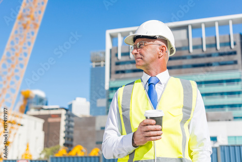 Engineer builder on construction site at sunny day with coffee in hand