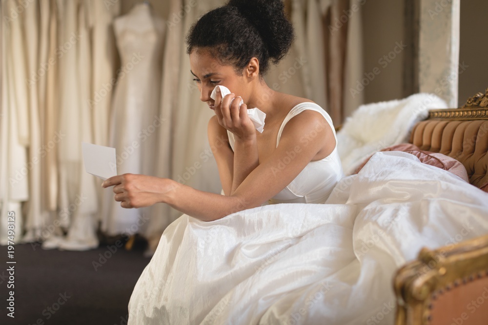 Young bride wiping her tears with tissue paper while reading a Young bride wiping her tears with tissue paper while reading a