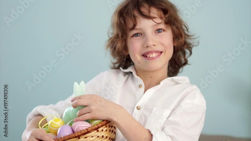 A child holds a Easter bunny and a set of decorative Easter eggs. The boy laughs cheerfully. Slow Motion photo